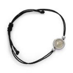 Art.-Nr. DUR-A1523 Schwarzes Baumwoll-Armband "Sandsturm" mit einem kleinen runden Element, gefüllt mit losem Strandsand, Muschelstückchen und kleiner Süßwasserperle, eingearbeitet in Glas und gefasst in rhodiniertem 925er Sterling-Silber. Länge verstellbar bis auf ca. 25 cm,