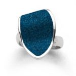 Art.-Nr. DUR-R5742 RING "BLAUE LAGUNE" STEINSAND Schmaler Ring mit einem aufgesetzten, geschwungenen Element in Form einer Insel, gefüllt mit blauem Steinsand und gefasst in rhodiniertem 925er Sterlingsilber. Die Ringschiene ist variabel zu verstellen.